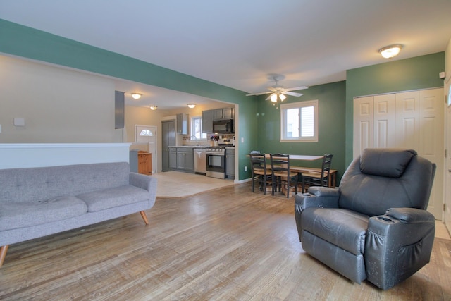 living room featuring sink, light hardwood / wood-style flooring, and ceiling fan