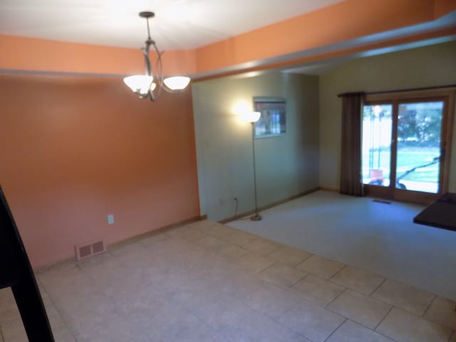 empty room featuring a chandelier and light tile patterned floors