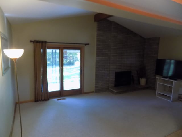 unfurnished living room featuring lofted ceiling, a fireplace, and carpet floors