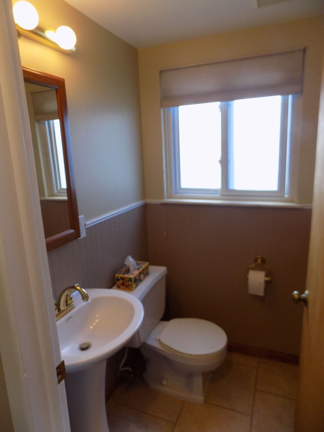 bathroom featuring wooden walls, tile patterned floors, and toilet