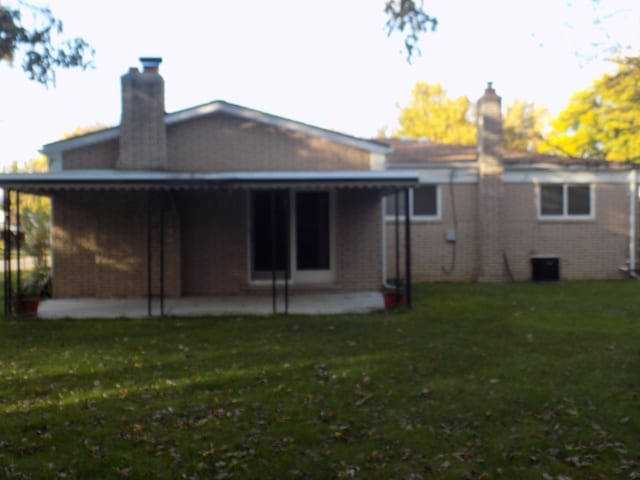 back of property featuring a lawn and a patio area