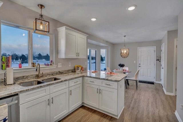 kitchen featuring stainless steel dishwasher, white cabinets, decorative light fixtures, sink, and kitchen peninsula