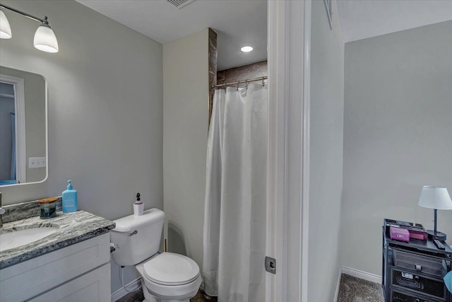 bathroom featuring toilet, walk in shower, and vanity