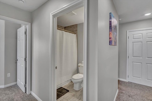 bathroom with toilet and a shower with shower curtain