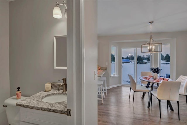 dining space with sink, an inviting chandelier, and hardwood / wood-style floors