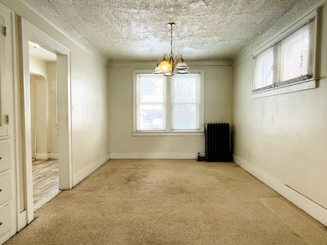 spare room with carpet, radiator heating unit, a notable chandelier, and a textured ceiling