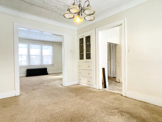 spare room with radiator, light colored carpet, a chandelier, and a textured ceiling