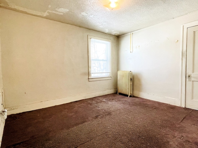 carpeted spare room featuring radiator and a textured ceiling