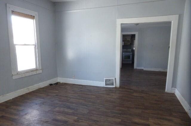 spare room featuring plenty of natural light and dark hardwood / wood-style flooring