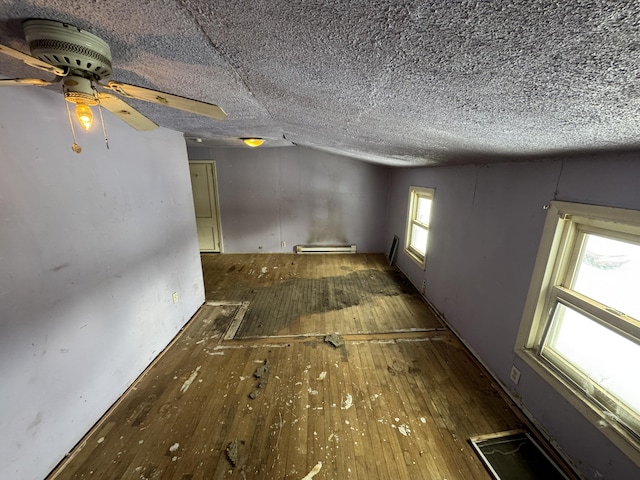 empty room featuring baseboard heating, a textured ceiling, vaulted ceiling, and dark hardwood / wood-style flooring