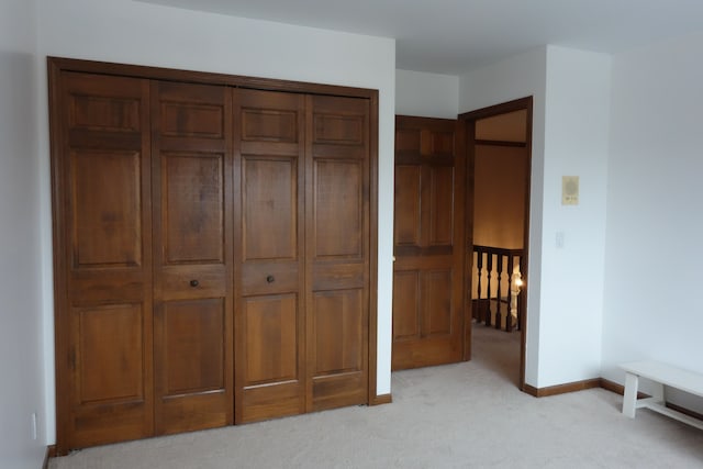 unfurnished bedroom with light colored carpet and a closet