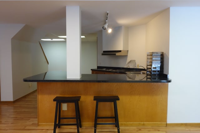 kitchen with a breakfast bar, sink, kitchen peninsula, gas stovetop, and light wood-type flooring