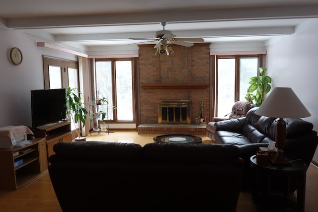 living room with beamed ceiling, ceiling fan, a fireplace, and light hardwood / wood-style flooring