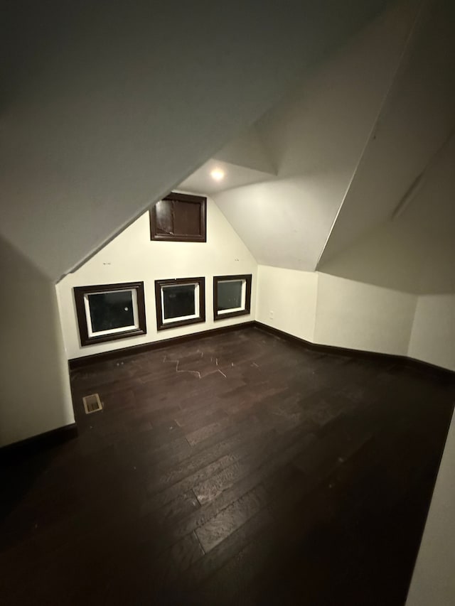 additional living space featuring lofted ceiling and dark wood-type flooring