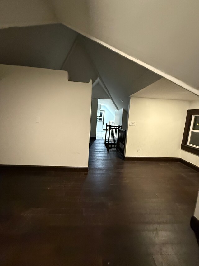 bonus room with dark wood-type flooring and vaulted ceiling