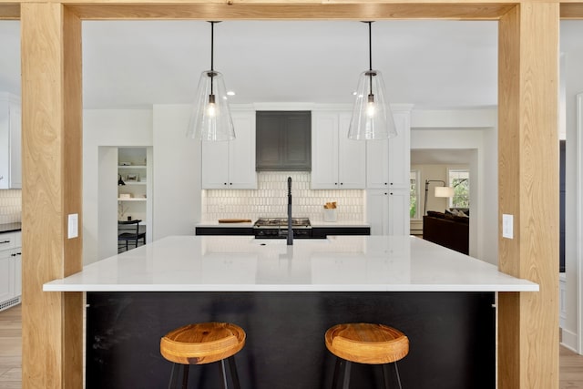 101 Carl Dr NE, Ada, MI 49301 - kitchen featuring backsplash, light wood-style floors, light countertops, a kitchen breakfast bar, and white cabinetry