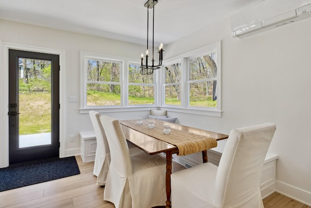 101 Carl Dr NE, Ada, MI 49301 - dining area featuring a wall unit AC, a chandelier, light wood-style flooring, and baseboards