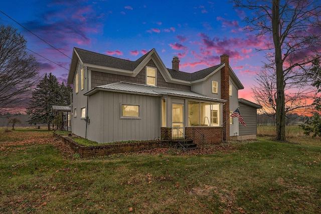 back house at dusk featuring a lawn