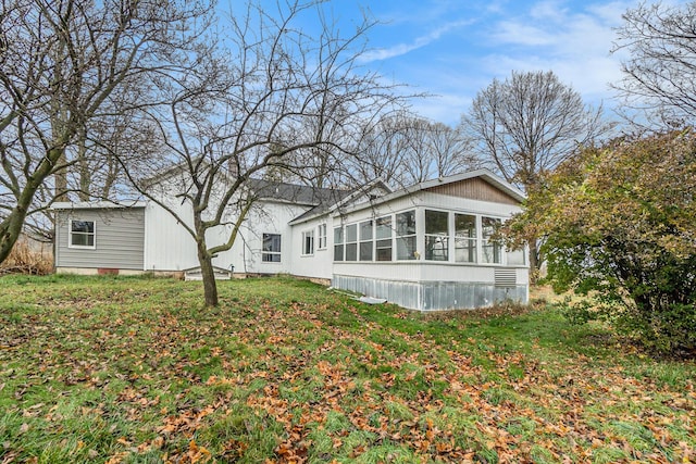 rear view of house with a lawn and a sunroom