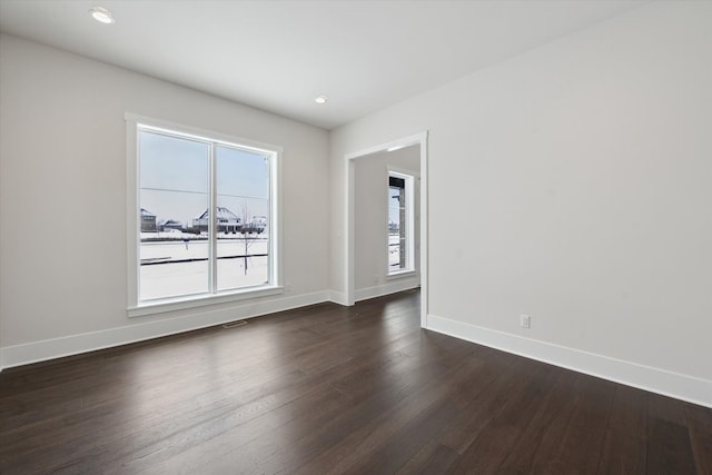 empty room with plenty of natural light and dark hardwood / wood-style flooring