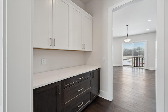 bar featuring dark brown cabinets, dark wood-type flooring, white cabinets, and decorative light fixtures