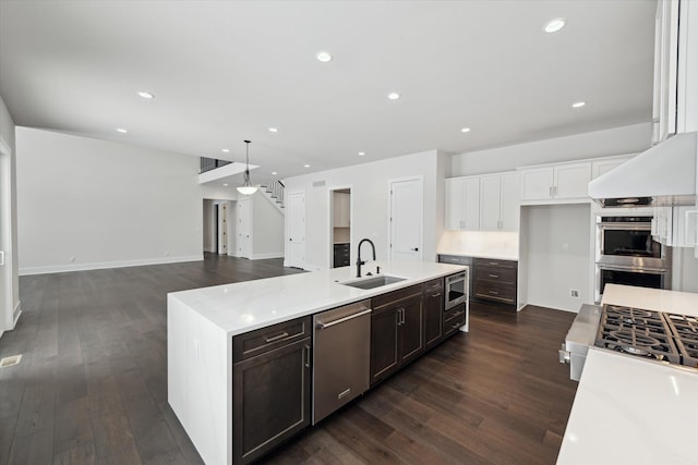 kitchen featuring appliances with stainless steel finishes, decorative light fixtures, white cabinetry, an island with sink, and sink