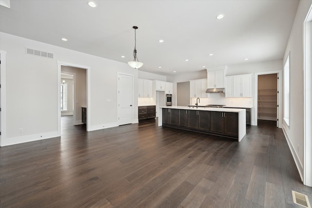 kitchen featuring sink, white cabinetry, a center island with sink, dark hardwood / wood-style flooring, and pendant lighting