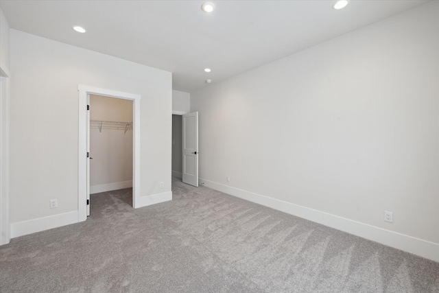 unfurnished bedroom featuring light colored carpet, a spacious closet, and a closet