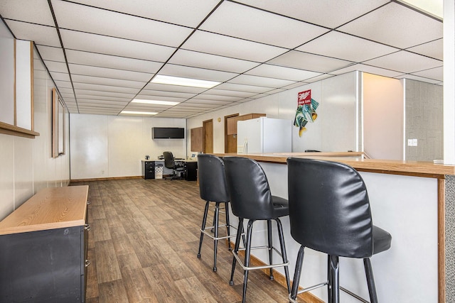 bar featuring hardwood / wood-style floors, a paneled ceiling, and white refrigerator