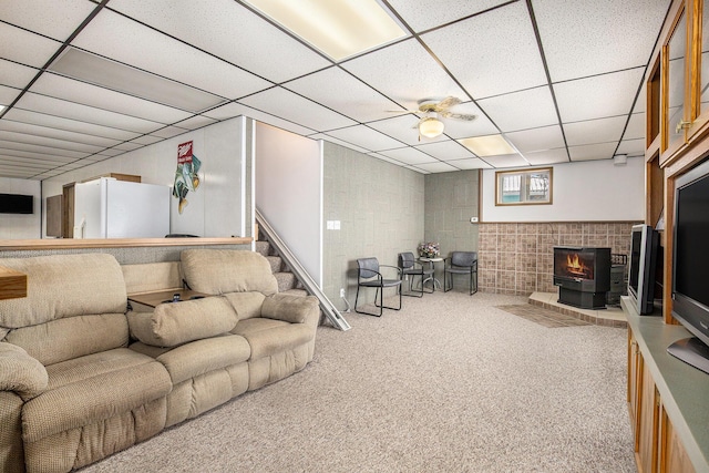 living room featuring a paneled ceiling, carpet flooring, and a wood stove