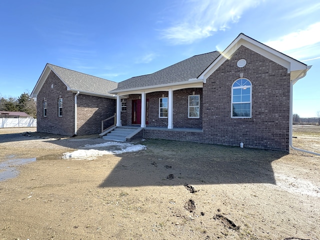 ranch-style home featuring brick siding and roof with shingles