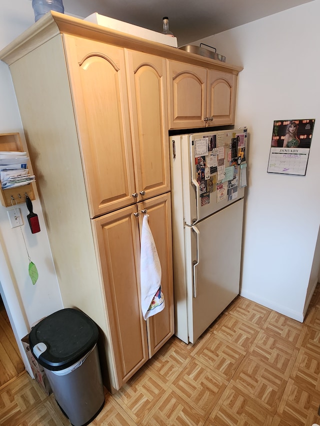 kitchen with light parquet flooring, light brown cabinetry, and white fridge