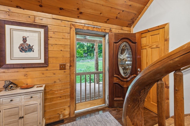 entryway featuring lofted ceiling, dark wood-type flooring, wooden ceiling, and wood walls