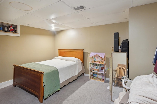 bedroom featuring a drop ceiling and light carpet