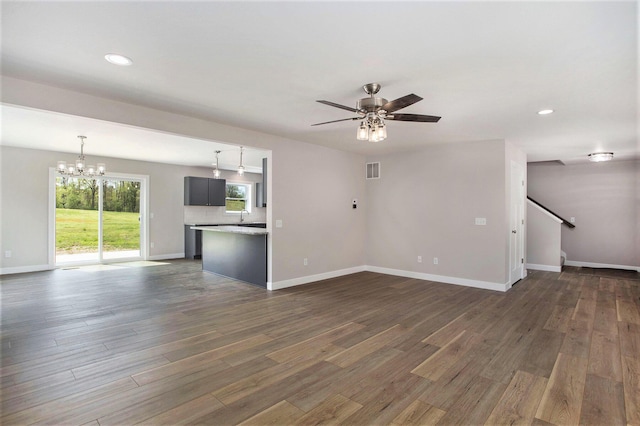 unfurnished living room featuring sink, dark hardwood / wood-style floors, and ceiling fan with notable chandelier