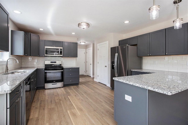 kitchen featuring sink, hanging light fixtures, light hardwood / wood-style flooring, stainless steel appliances, and decorative backsplash