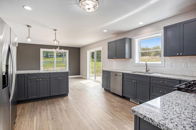 kitchen with pendant lighting, stainless steel appliances, sink, and tasteful backsplash