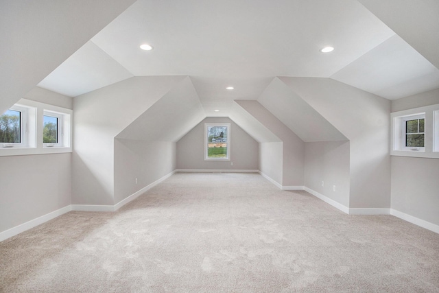 bonus room with vaulted ceiling and light carpet