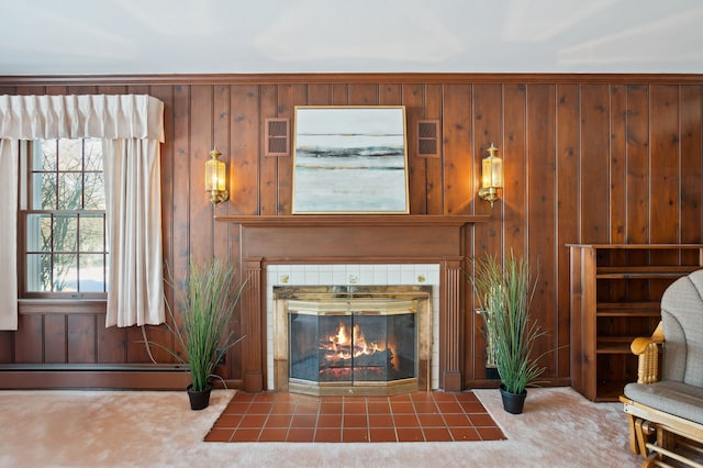 unfurnished living room with a baseboard radiator, a tiled fireplace, carpet, and wood walls