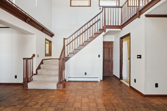 stairs featuring a baseboard radiator, parquet flooring, and a towering ceiling