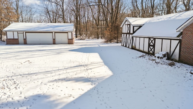 yard layered in snow featuring a garage and an outbuilding