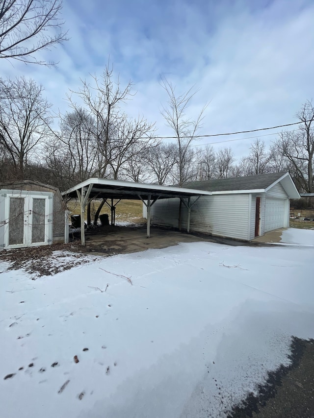 snow covered parking area featuring a garage and a carport