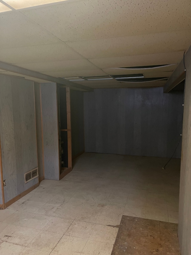 finished basement featuring a paneled ceiling and visible vents