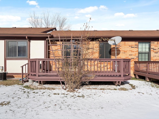 snow covered back of property featuring a wooden deck