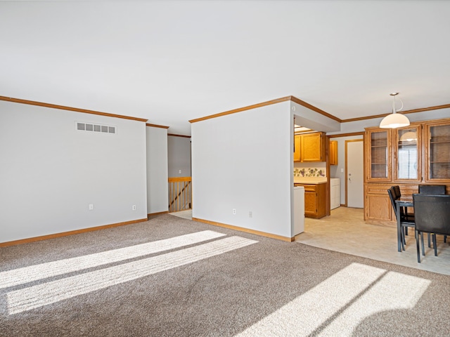 unfurnished living room with washer / clothes dryer, ornamental molding, and light carpet