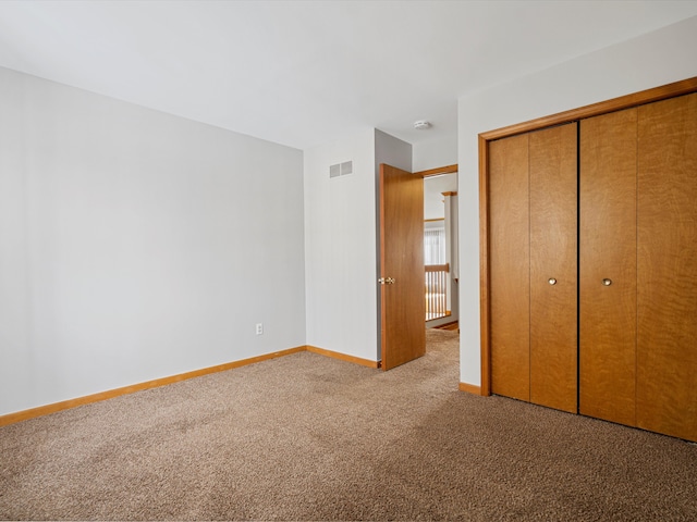 unfurnished bedroom featuring light colored carpet and a closet