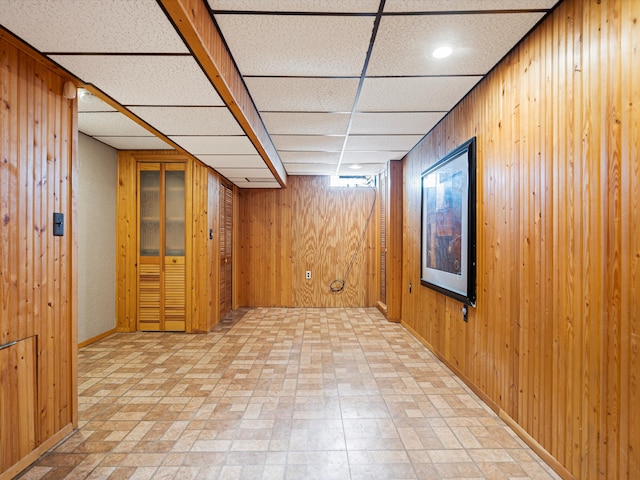 basement with wooden walls and a paneled ceiling