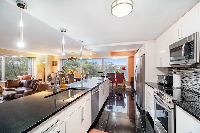 kitchen with pendant lighting, sink, white cabinetry, and appliances with stainless steel finishes