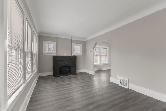 unfurnished living room with dark wood-type flooring and a brick fireplace