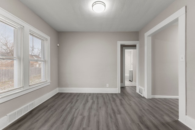 unfurnished room featuring dark hardwood / wood-style floors and a textured ceiling